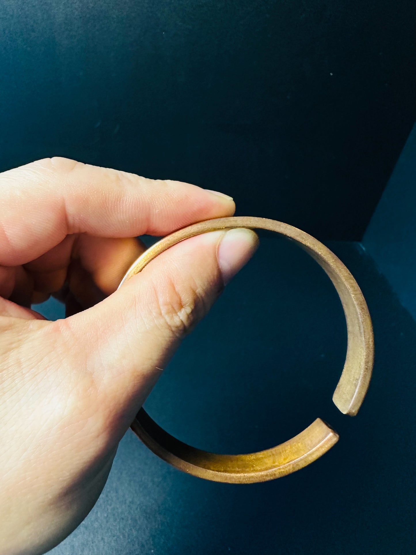 Open copper cuff bracelet held in hand, showing the adjustable gap for a custom wrist fit