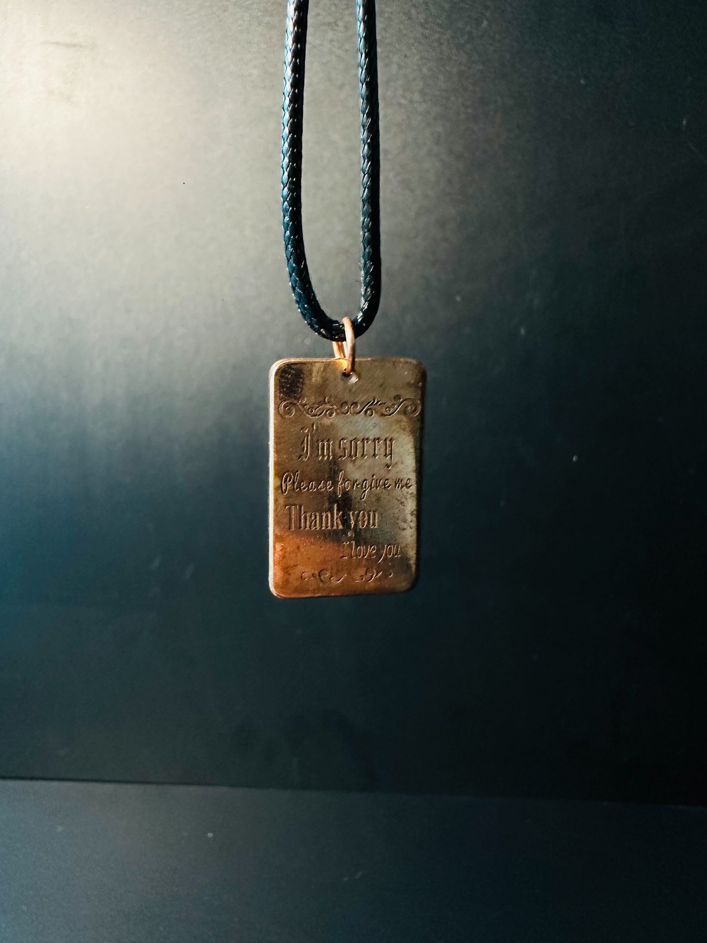 Ho'oponopono prayer copper pendant hanging on a black cord, a forgiveness reminder for meditation