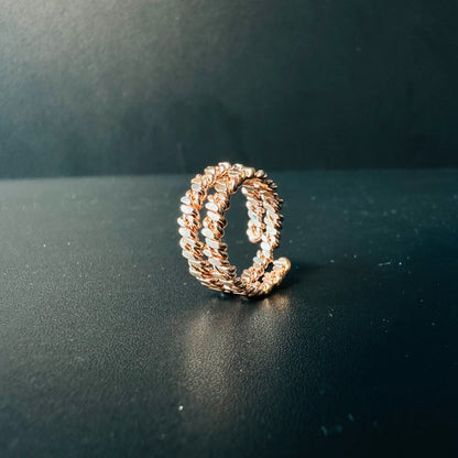 Handmade copper braided ring with two twisted rope bands and adjustable open back, on a dark surface