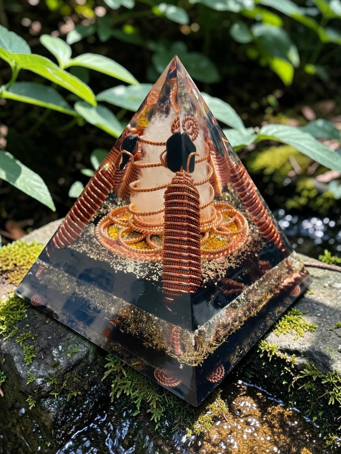 Kim tự tháp năng lượng Lost Cubit Tensor Rings làm từ đồng nguyên chất, có các vòng dây đồng xoắn ốc và đá bên trong, đặt trên đá phủ rêu.