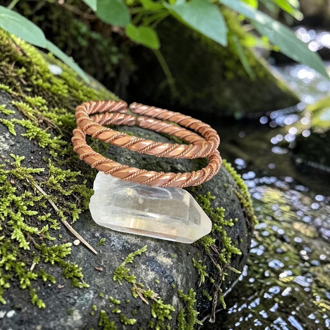 Vòng cổ đồng Triple Tensor Sacred hình tròn xoắn, chế tác thủ công từ đồng nguyên chất, đặt trên đá thạch anh.