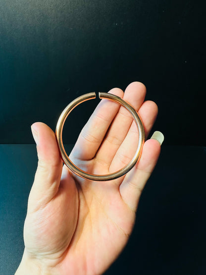 Open copper bangle held in hand, showing how the band adjusts to fit the wrist