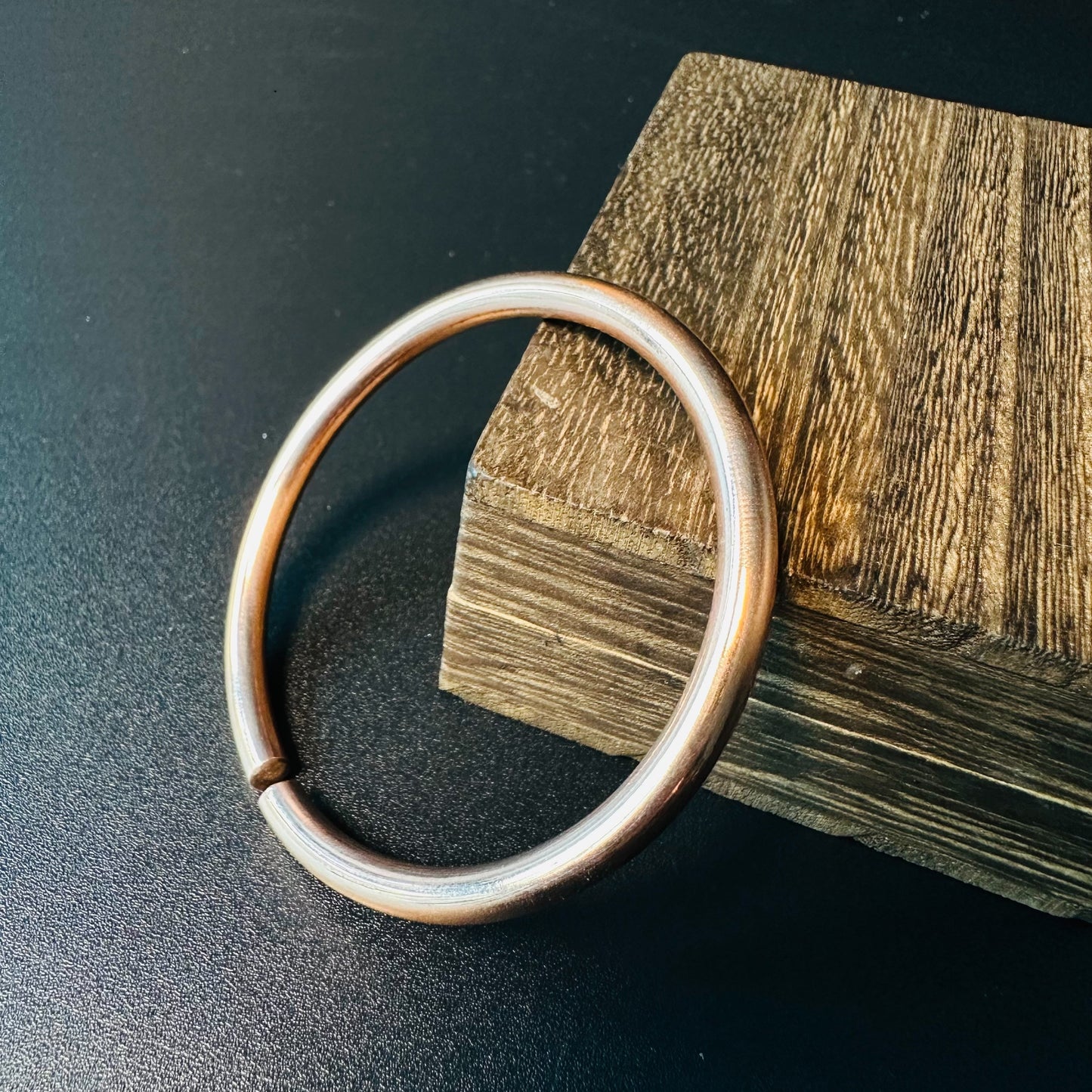 Handmade copper bangle bracelet with a smooth round band and warm patina