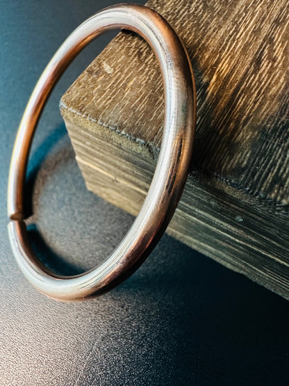 Close-up of the open copper bangle showing its adjustable gap and polished finish