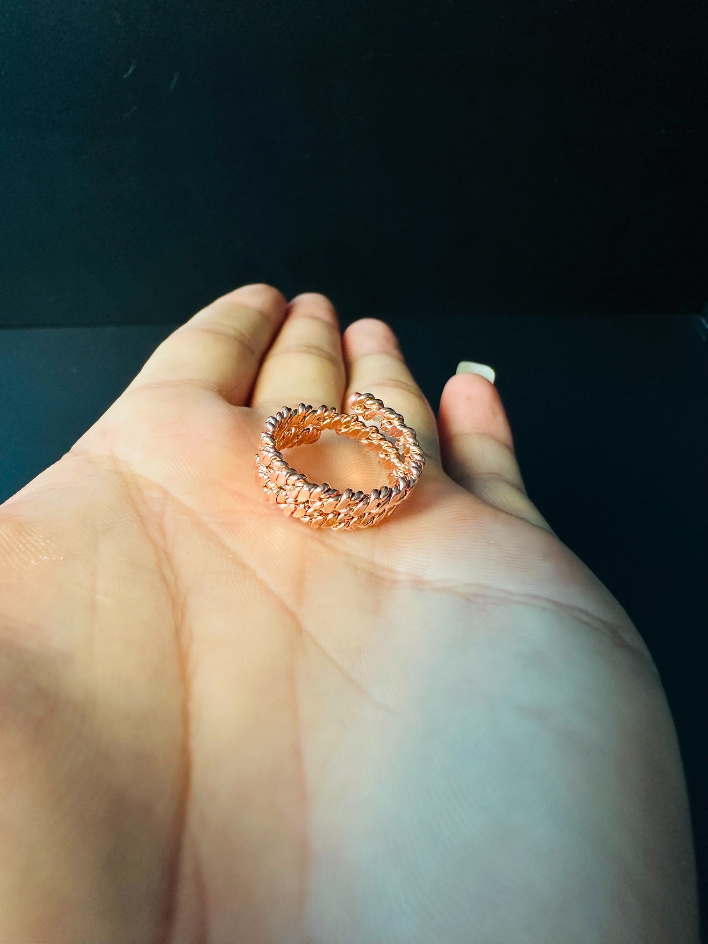 Adjustable copper ring resting on an open palm, showing its size against the hand