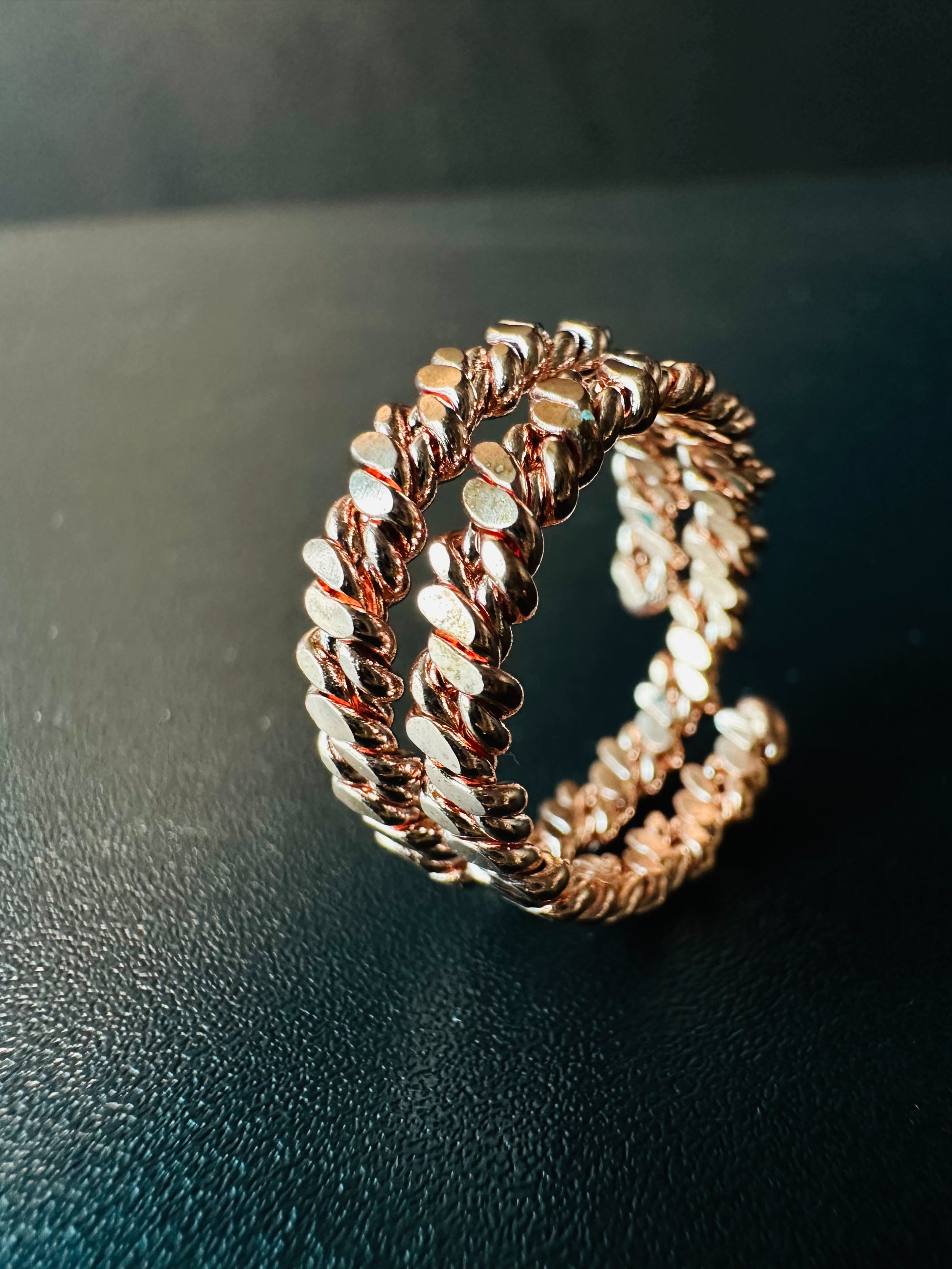 Side angle of the twisted copper ring showing the depth of its double rope band and warm rose-gold shine