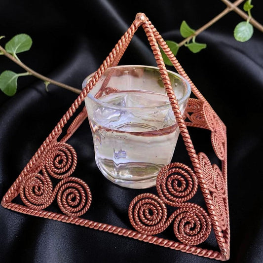 Side view of a handmade copper charging pyramid showing the open frame and inner coil