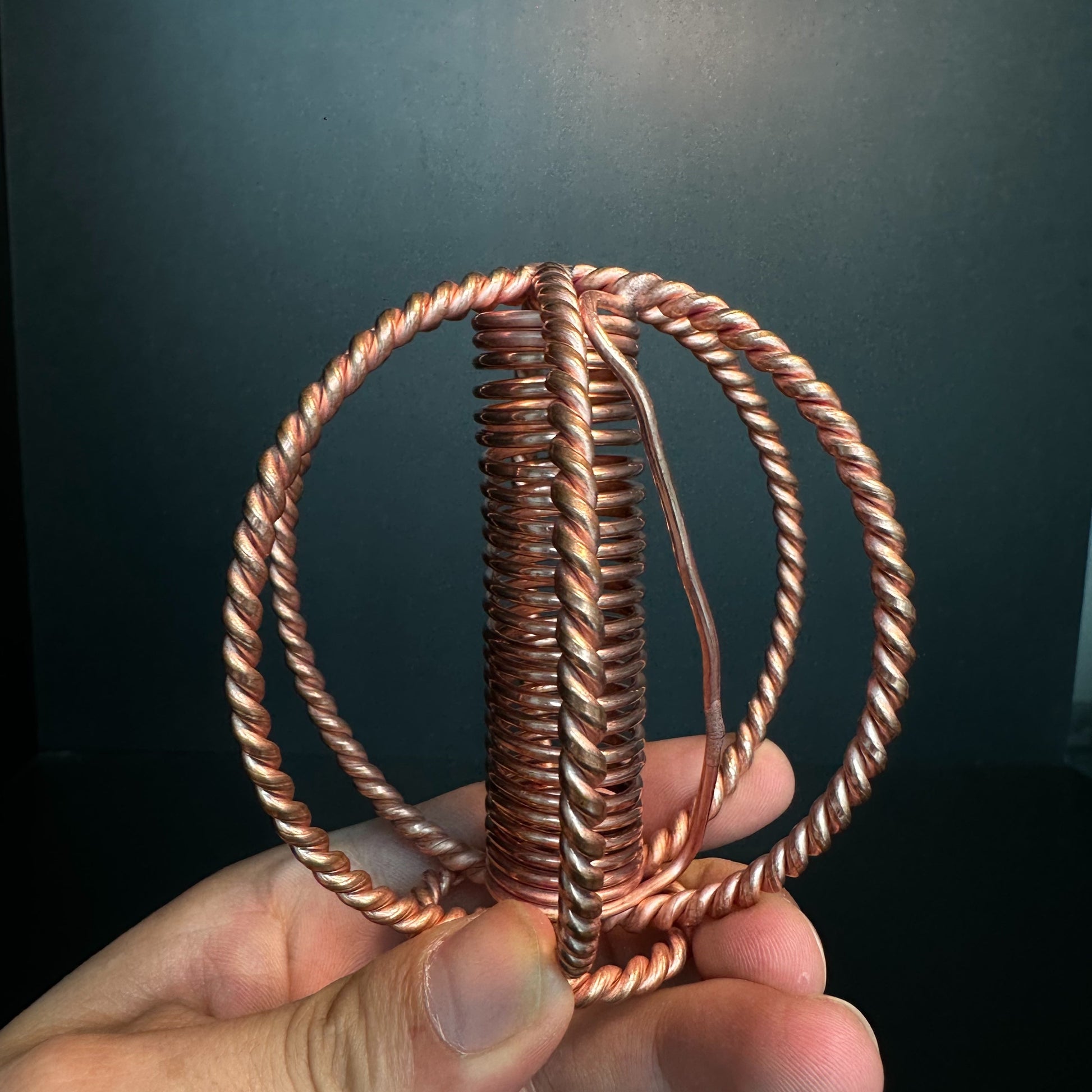 Angled view of copper coil sphere showing crossed wire rings
