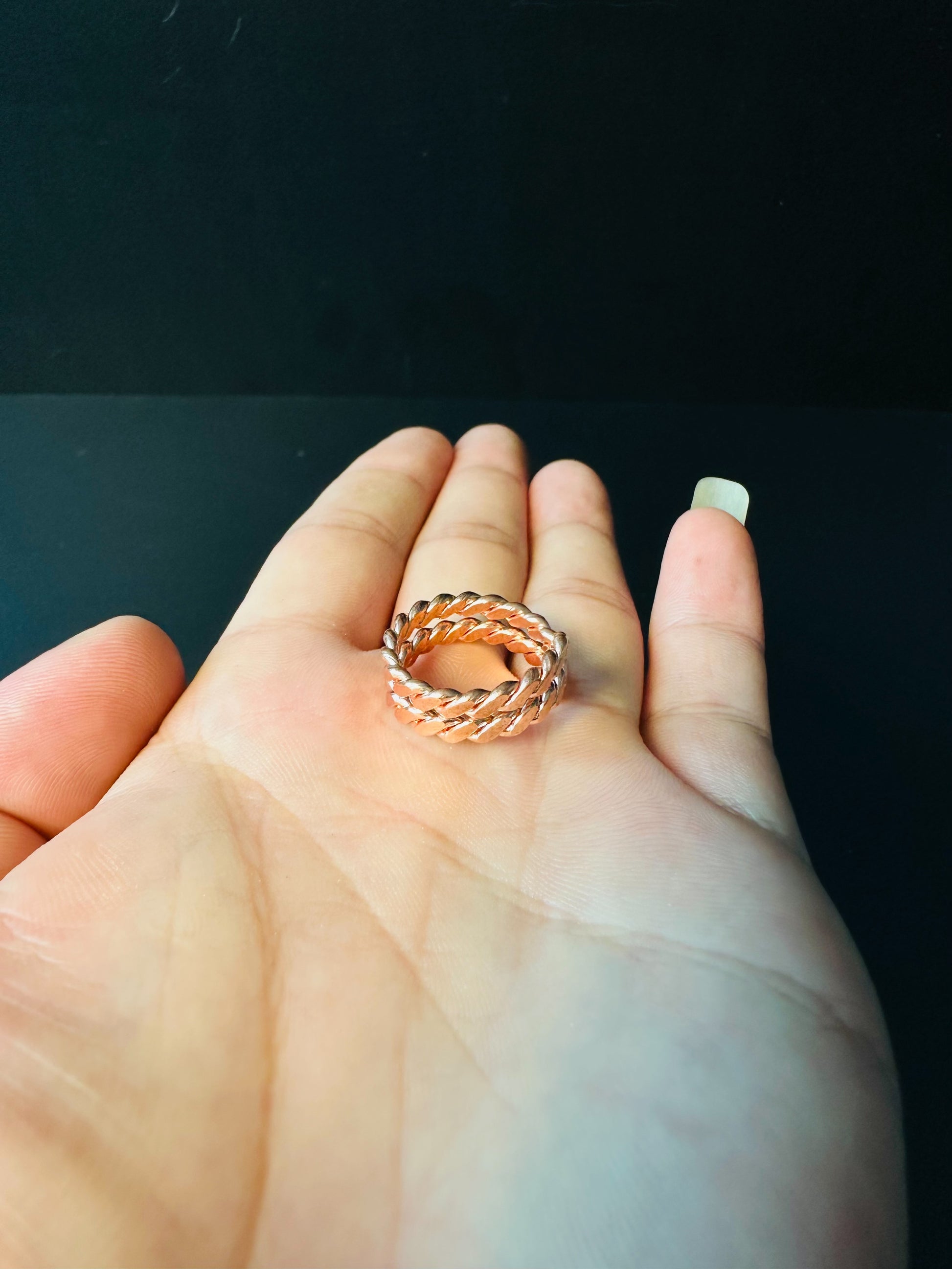 Copper Cuban link ring resting on a palm, showing its size and woven link texture