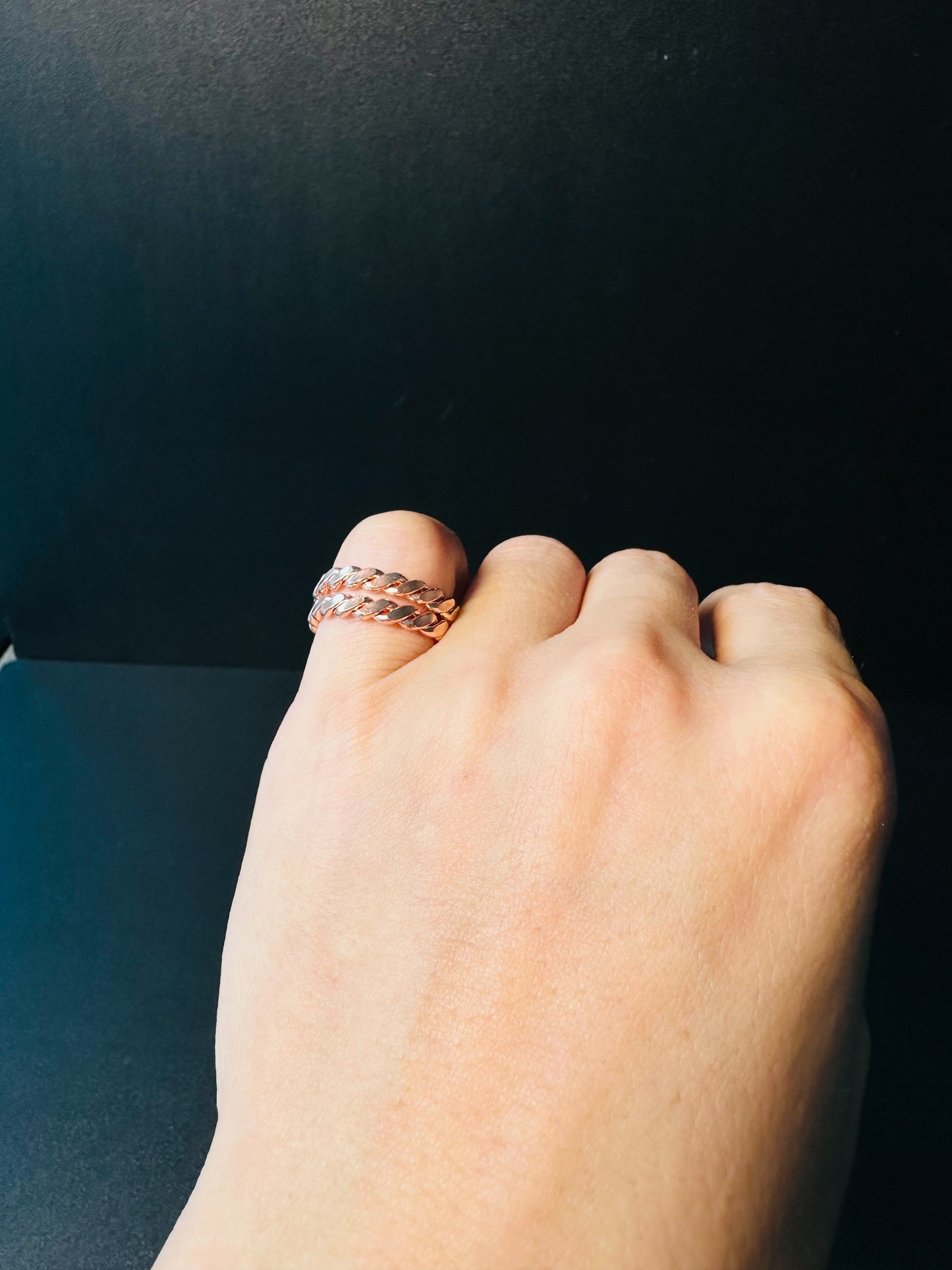 Copper link ring worn on the hand, catching light across each chain link