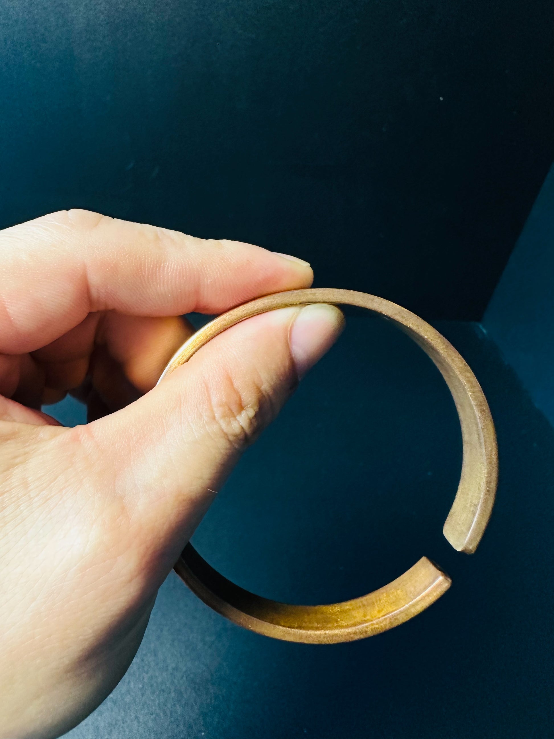 Open copper cuff bracelet held in hand, showing the adjustable gap for a custom wrist fit