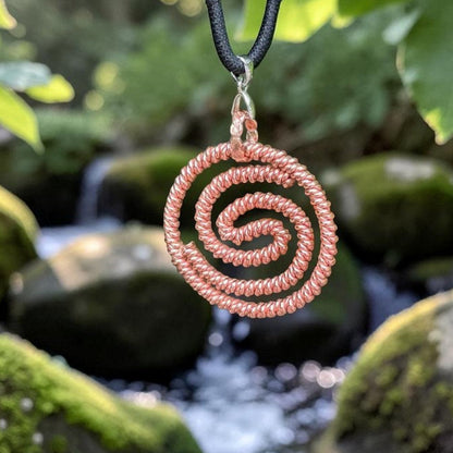 Copper double spiral pendant shaped to 144MHz, two hand-coiled spirals, hanging over a mossy rock