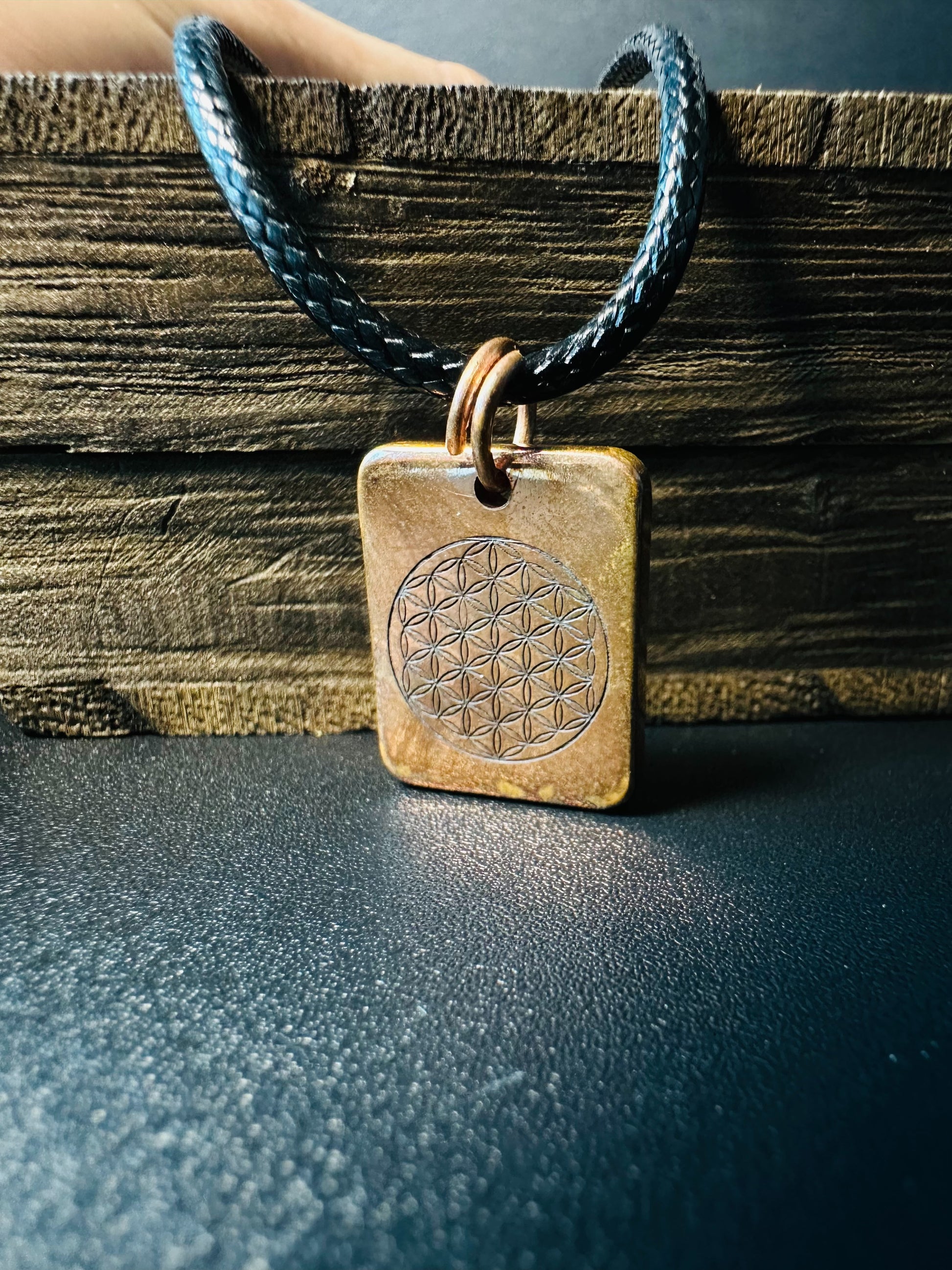 Reverse side of the copper pendant showing the engraved Flower of Life symbol with warm patina