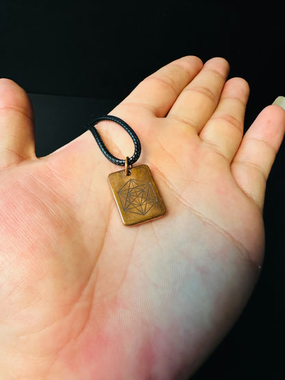 Close view of the Metatron's Cube engraving and copper patina held between fingers