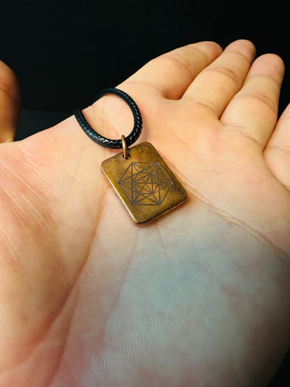 Copper sacred geometry pendant held in a palm, showing its compact everyday-wear size