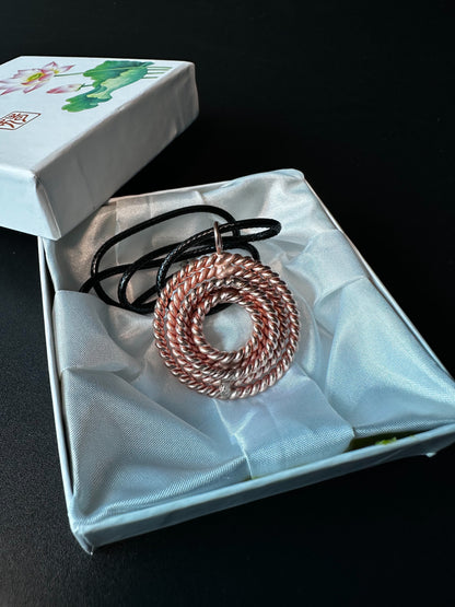 Handmade copper sacred geometry pendant in sealed gift packaging held in hand, tensor necklace