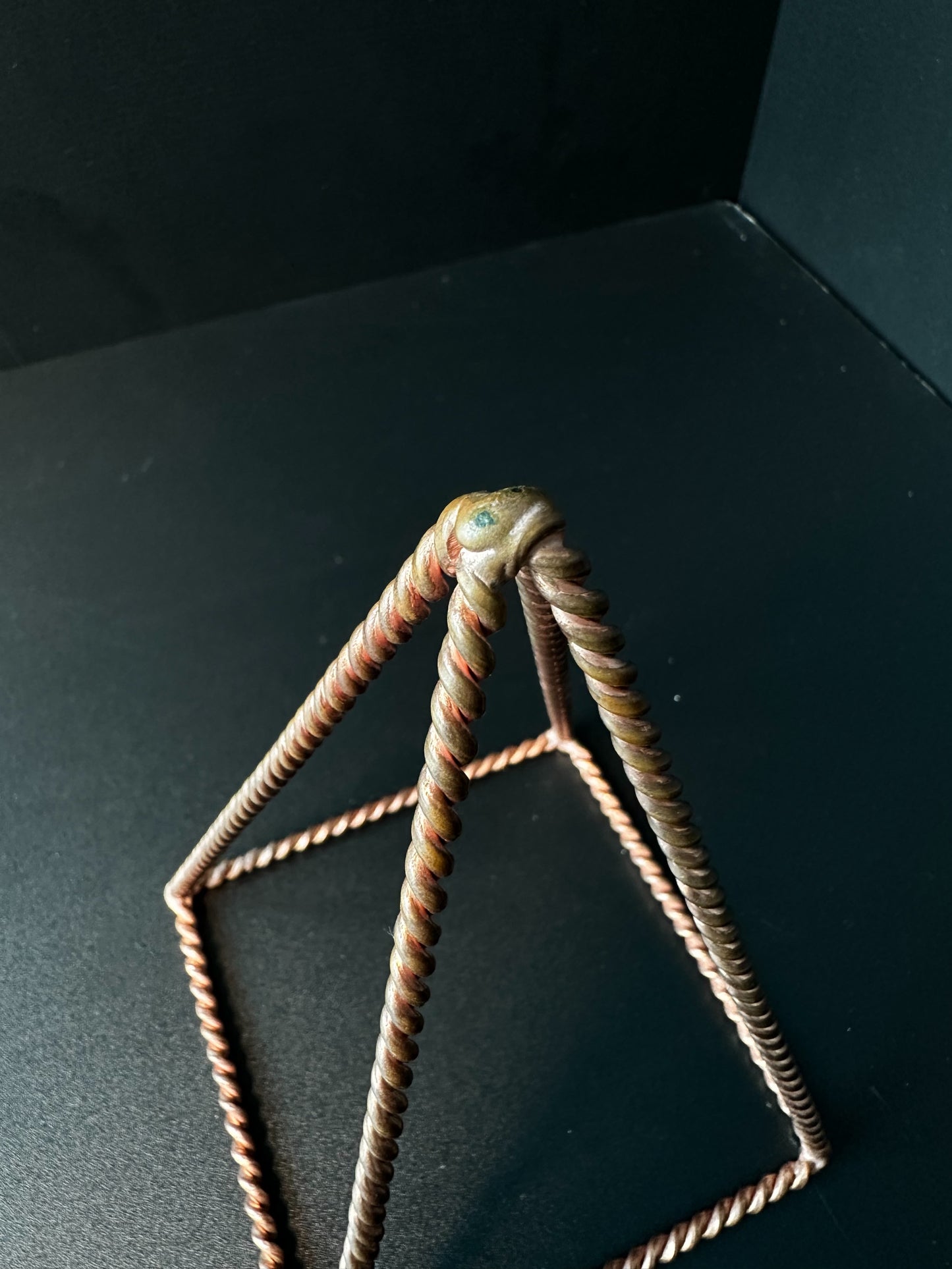 Close-up of hand-twisted pure copper wire apex, EMF protection energy pyramid detail
