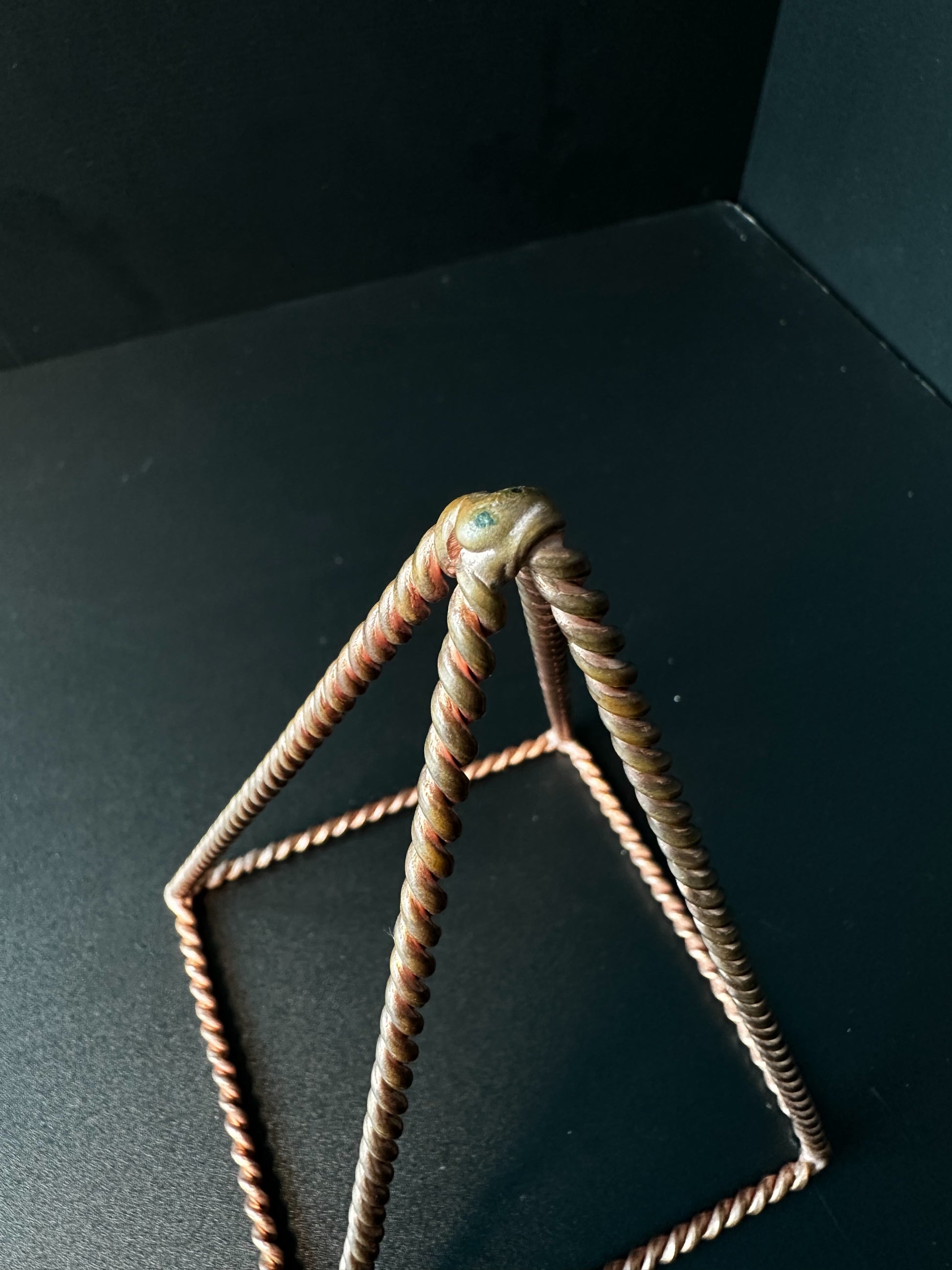 Close-up of hand-twisted pure copper wire apex, EMF protection energy pyramid detail

