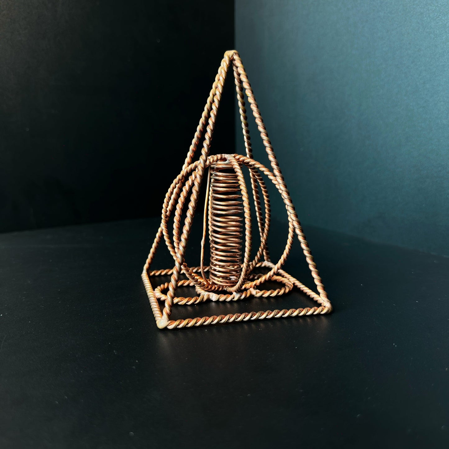 Handmade copper pyramid with a wound copper coil standing at its center