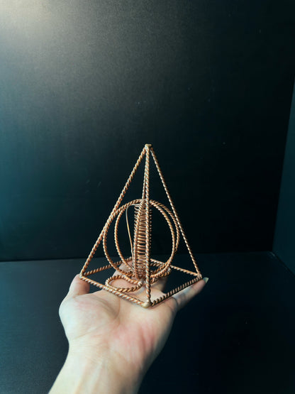 Copper pyramid coil held up as a sacred geometry piece for an altar or meditation space