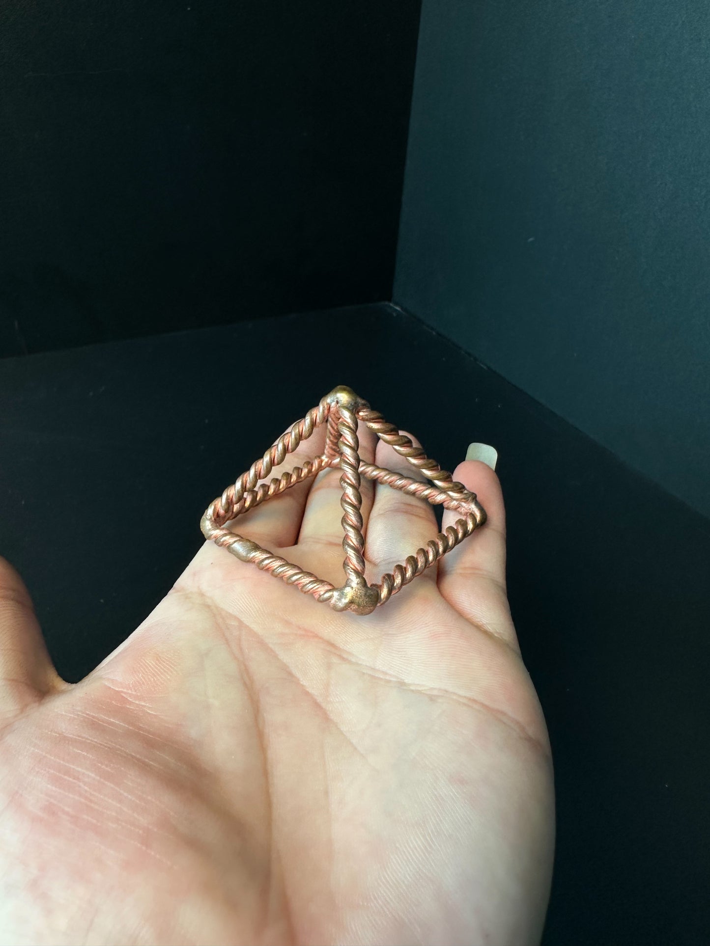 Copper pyramid frame held in hand to show its size