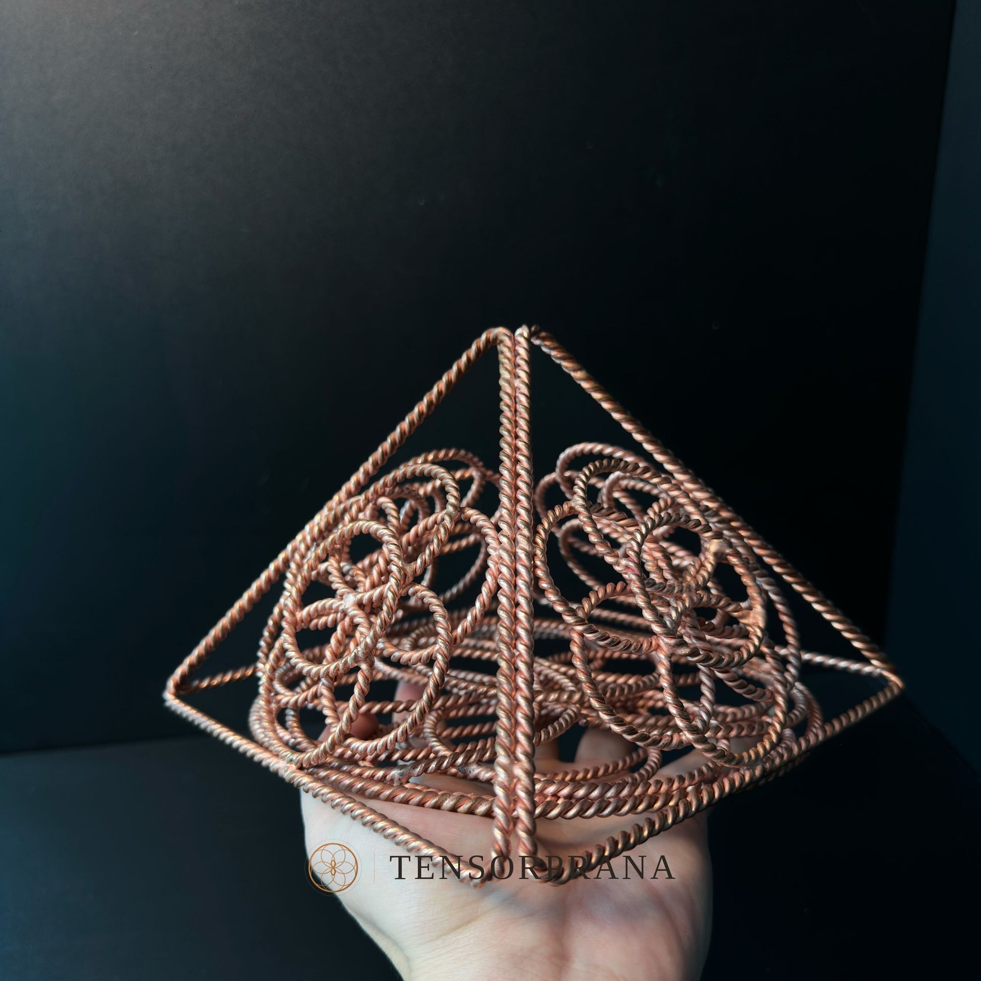 Palm-sized copper pyramid held in a hand, showing its scale and pointed apex