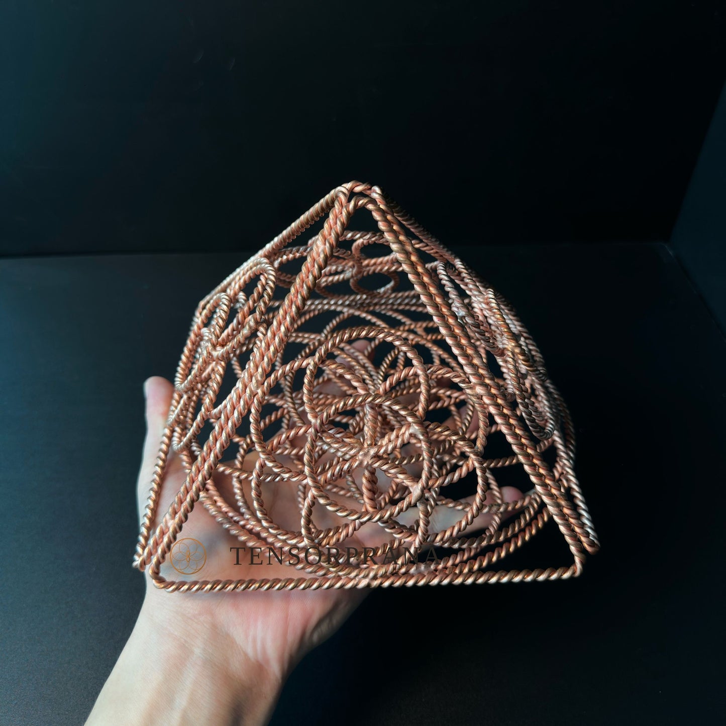 Copper pyramid held up as a sacred geometry piece for an altar or meditation space