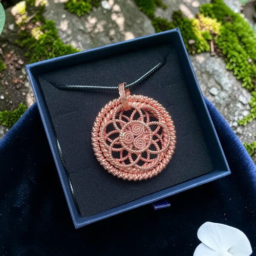 Copper sacred geometry pendant with an intricate woven mandala design, presented in a black gift box
