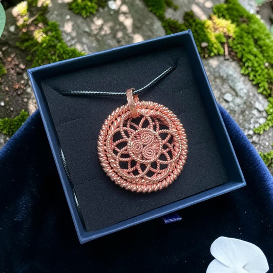 Copper sacred geometry pendant with an intricate woven mandala design, presented in a black gift box
