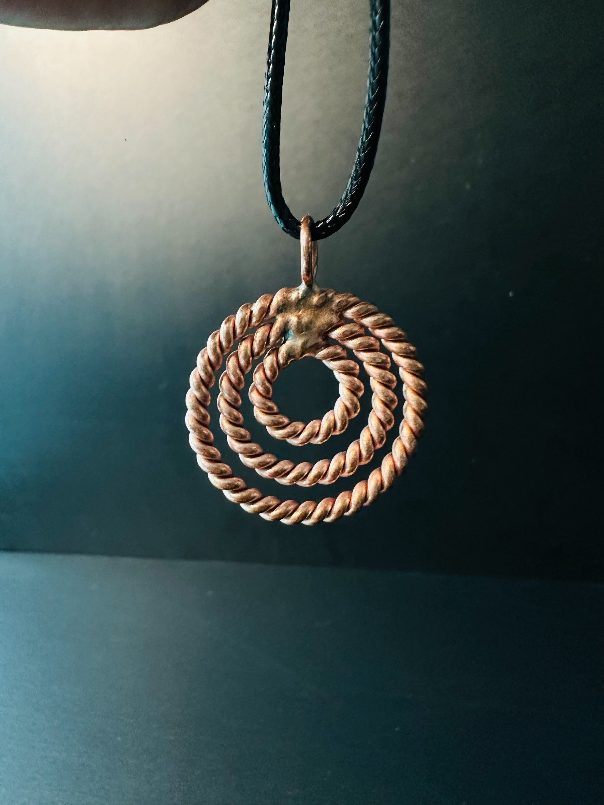 Copper bail and black waxed cord detail on spiral pendant