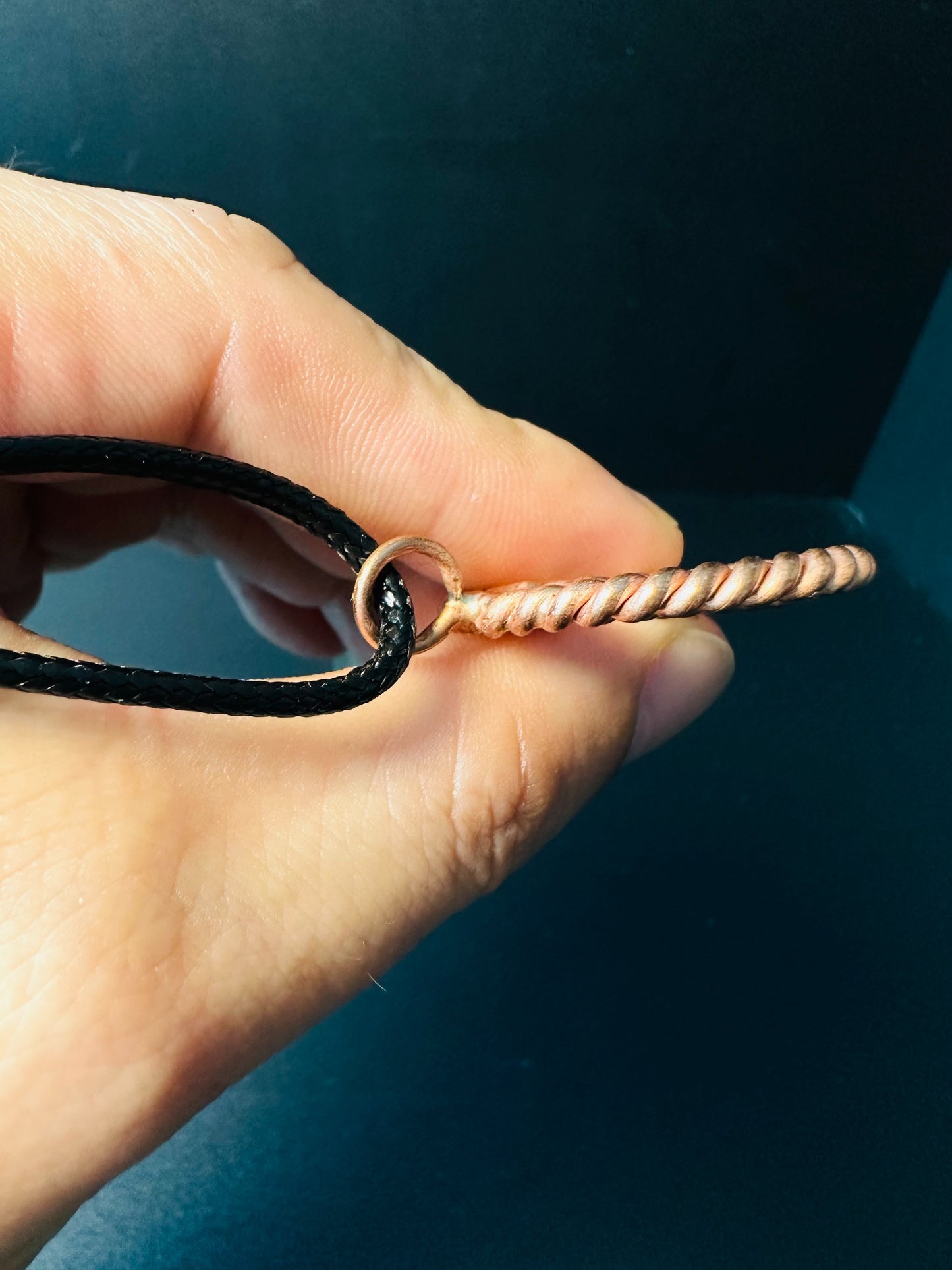 Copper spiral pendant held in hand to show size