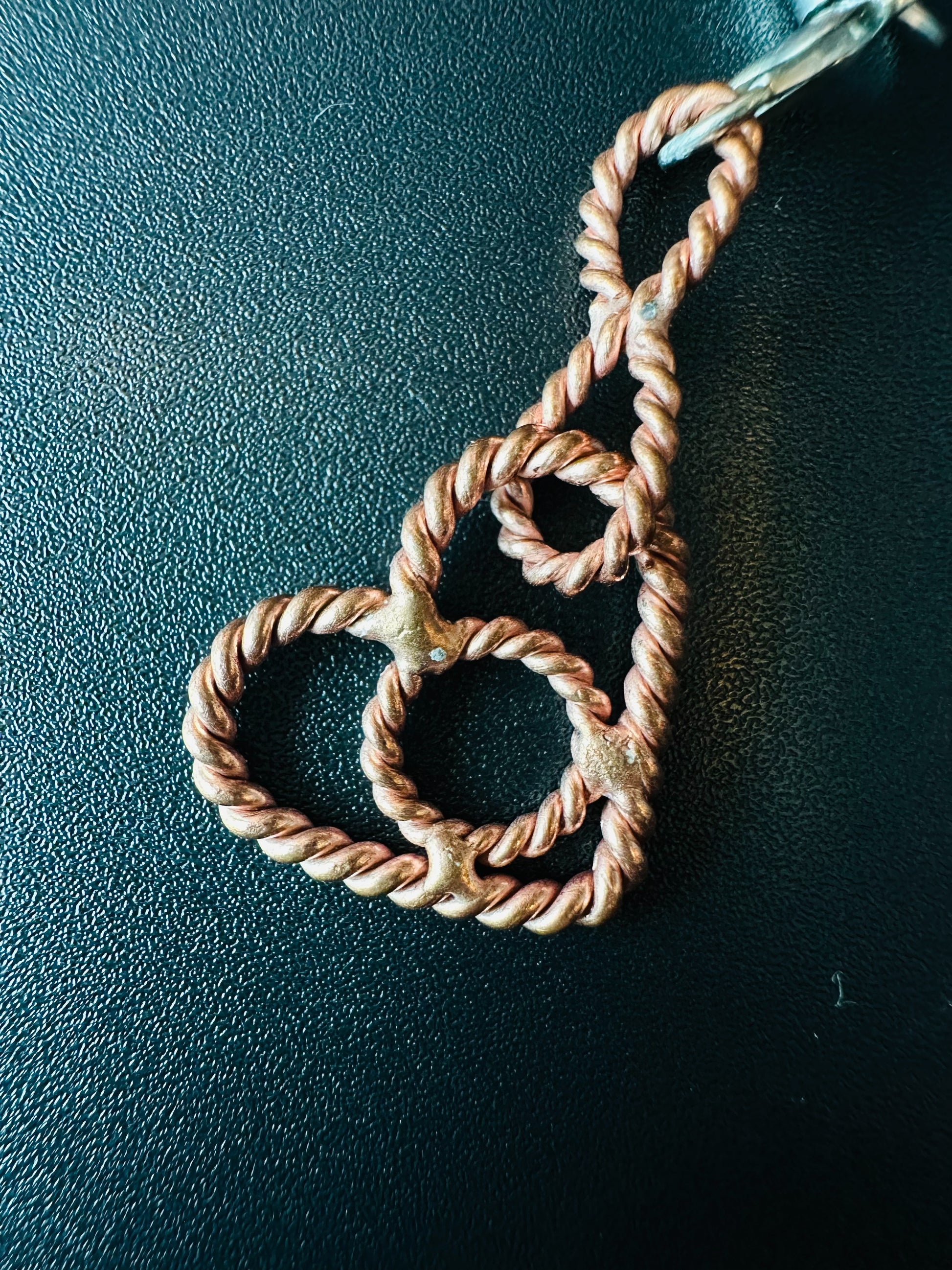 Close-up of the twisted copper heart charm with small tensor rings curled inside