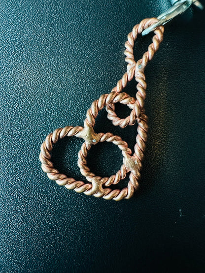 Close-up of the twisted copper heart charm with small tensor rings curled inside