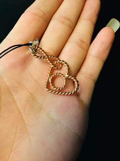 Copper tensor heart charm held in a palm, showing its small lightweight size
