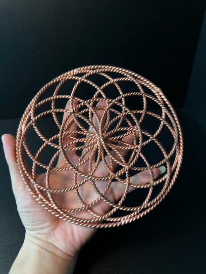 Palm-sized copper torus sphere held in a hand, showing its scale and woven depth
