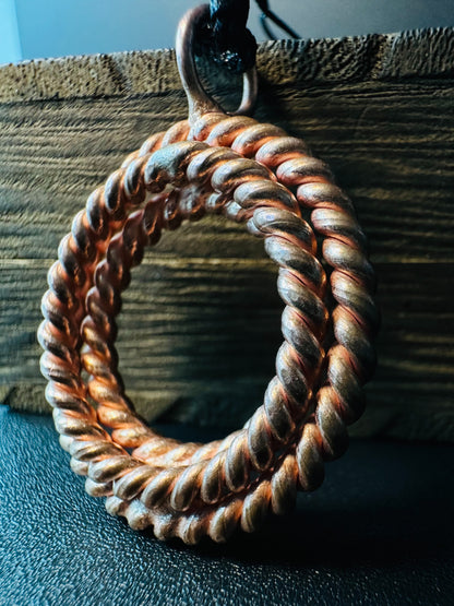 Copper circle pendant showing twisted two-strand rope texture