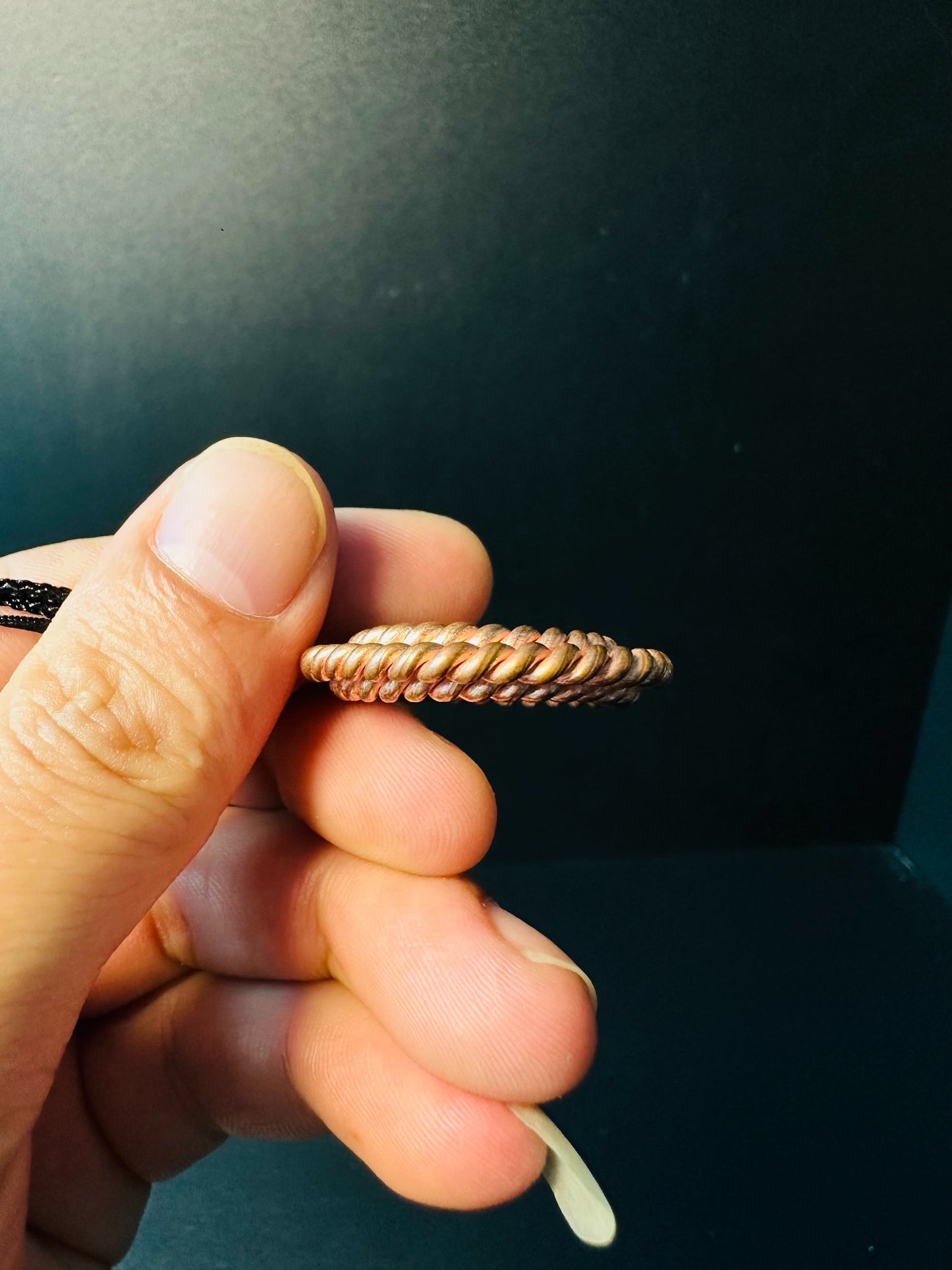 Copper twisted ring pendant held in hand to show compact size