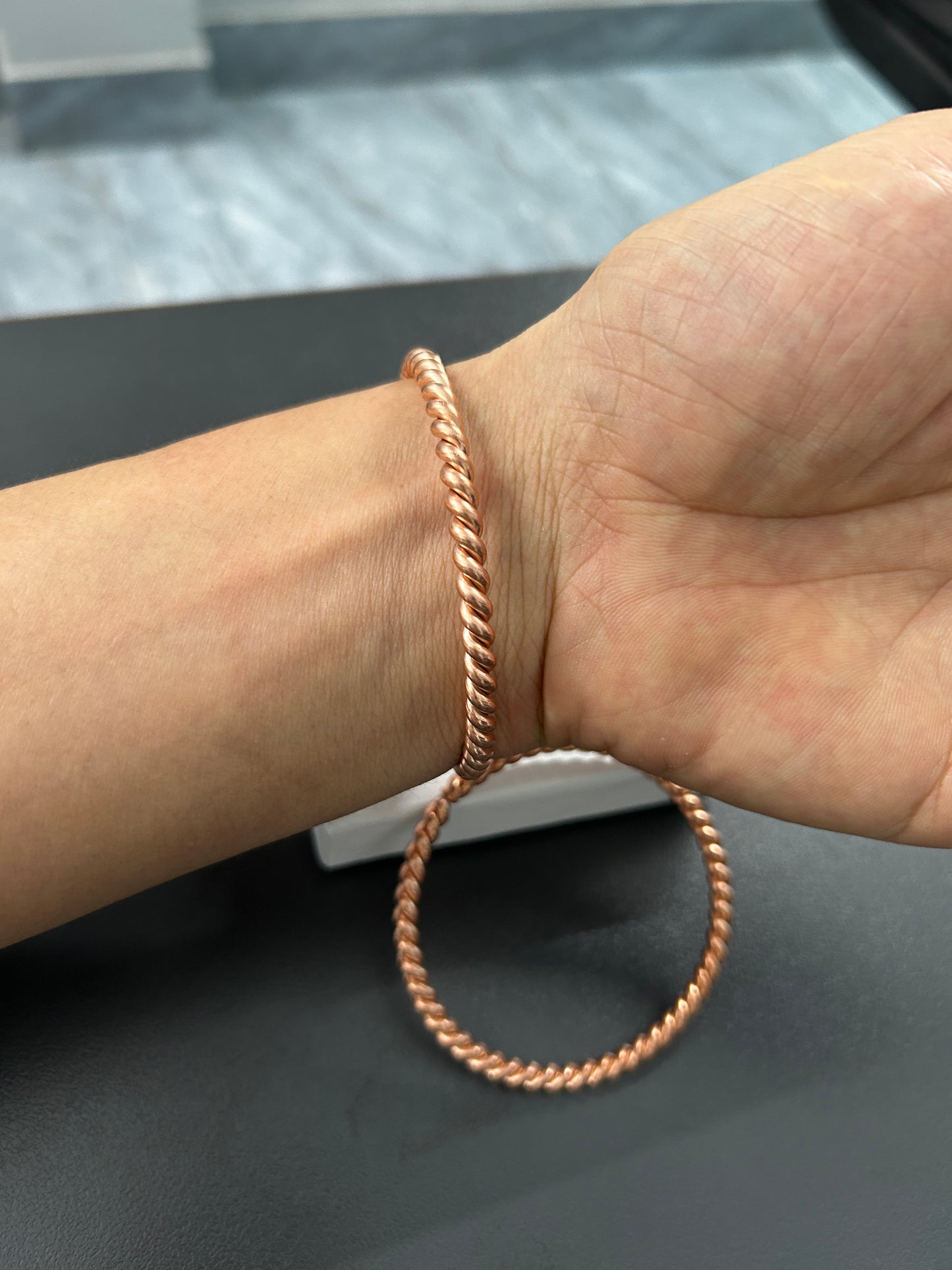 Close-up of twisted rope texture on handmade pure copper bangle, spiral copper detail.