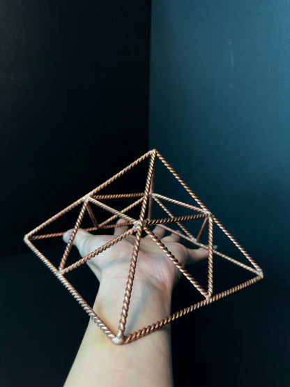 Large twisted copper wire pyramid held in hand, handmade crystal charging tool