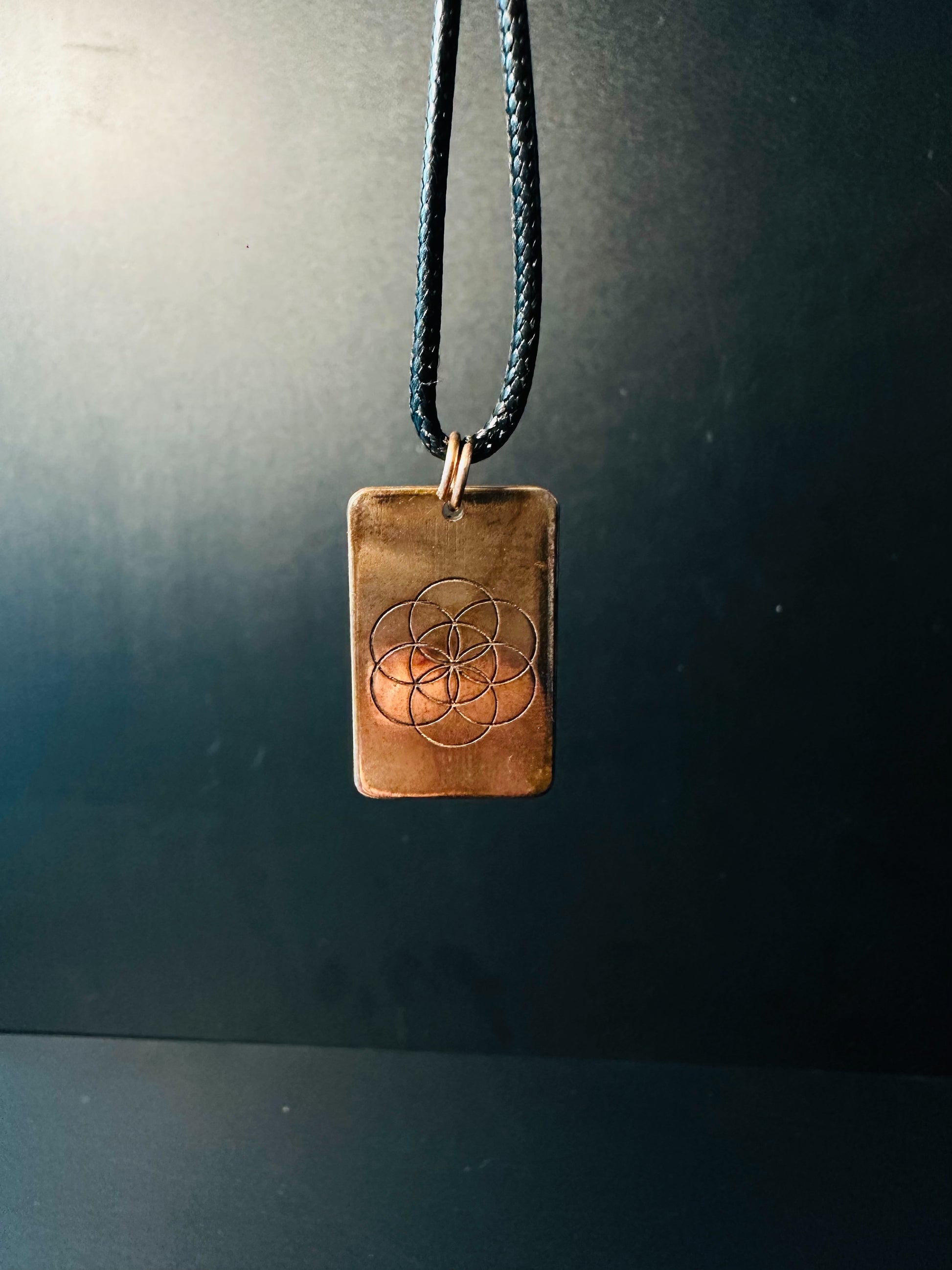 Copper Seed of Life pendant hanging from an adjustable cord, catching soft light