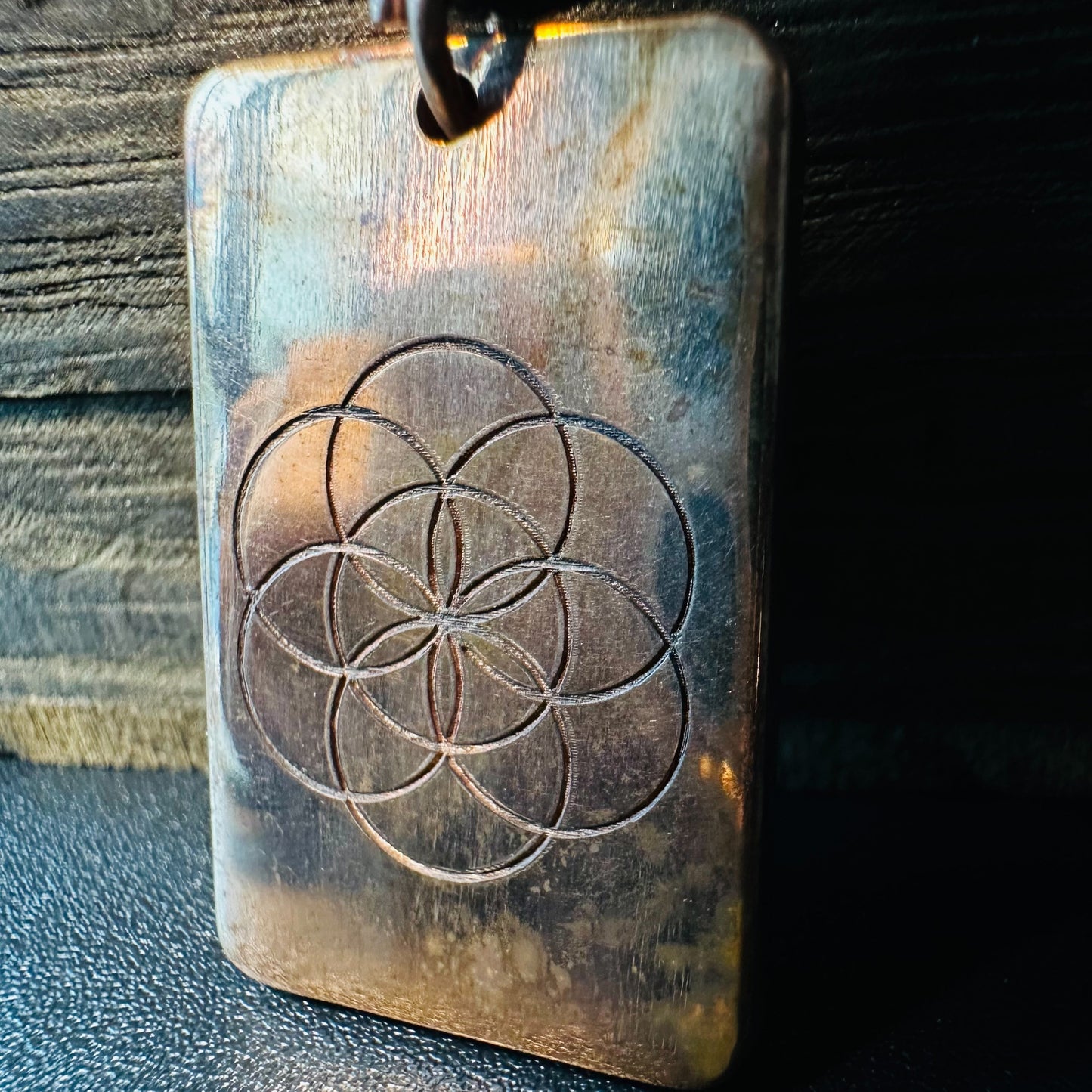 Close view of the Seed of Life engraving and warm copper patina on the rectangular pendant