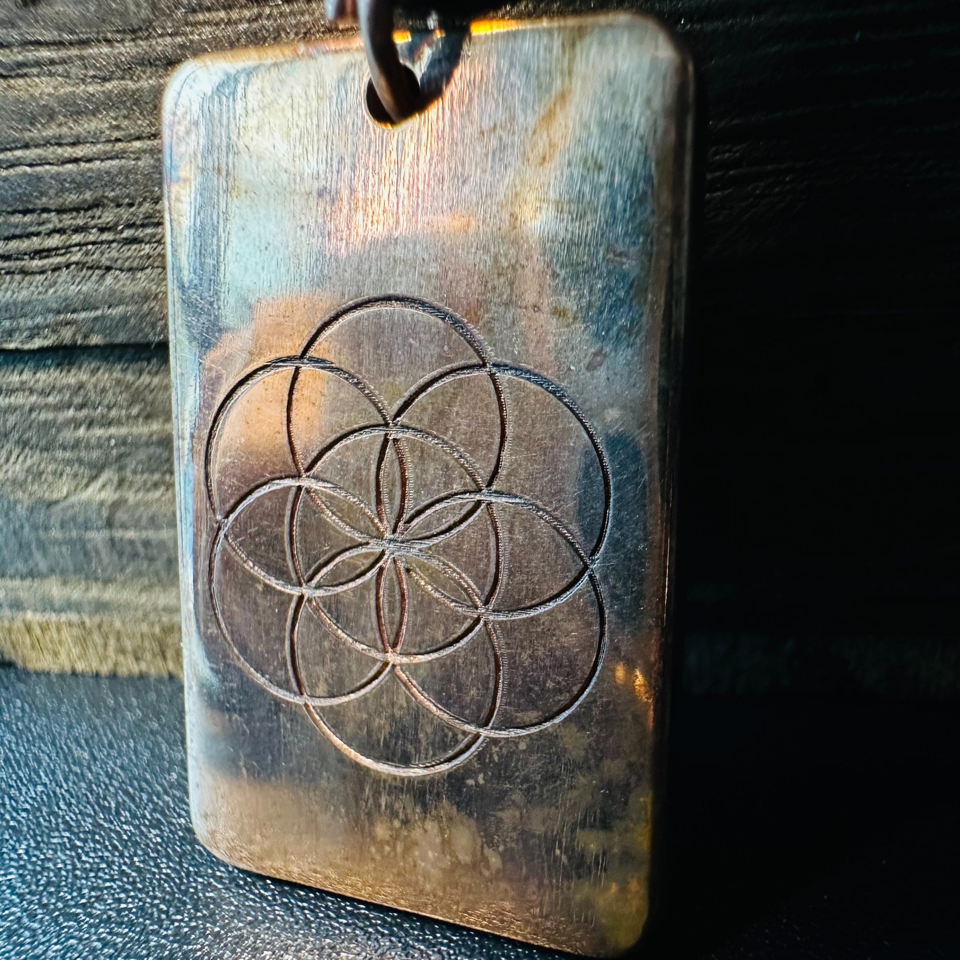 Close view of the Seed of Life engraving and warm copper patina on the rectangular pendant