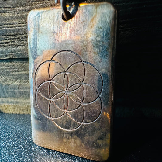 Close view of the Seed of Life engraving and warm copper patina on the rectangular pendant
