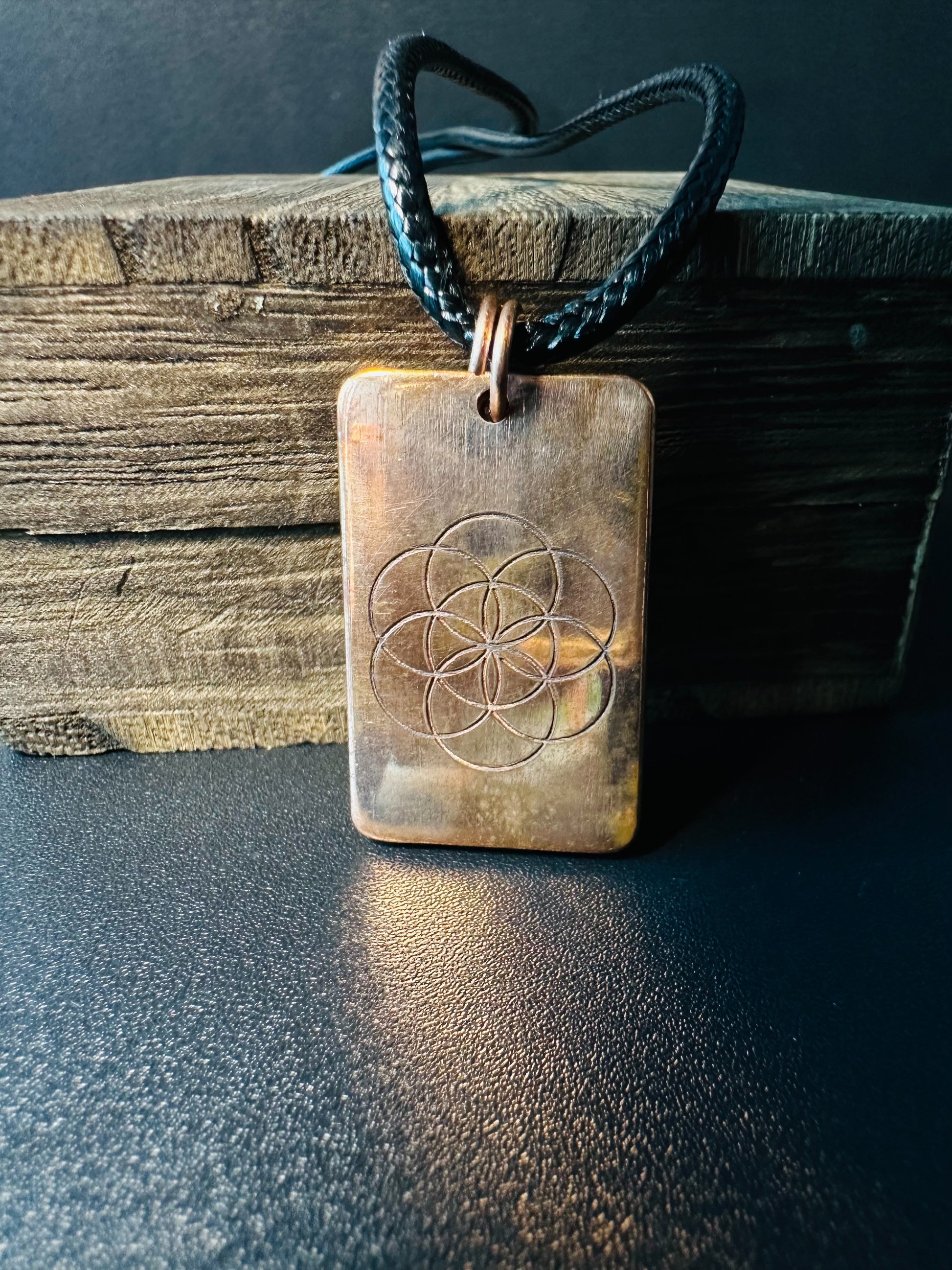 Reverse side of the copper pendant showing the engraved Seed of Life sacred geometry symbol