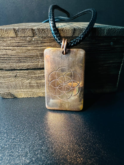 Reverse side of the copper pendant showing the engraved Seed of Life sacred geometry symbol