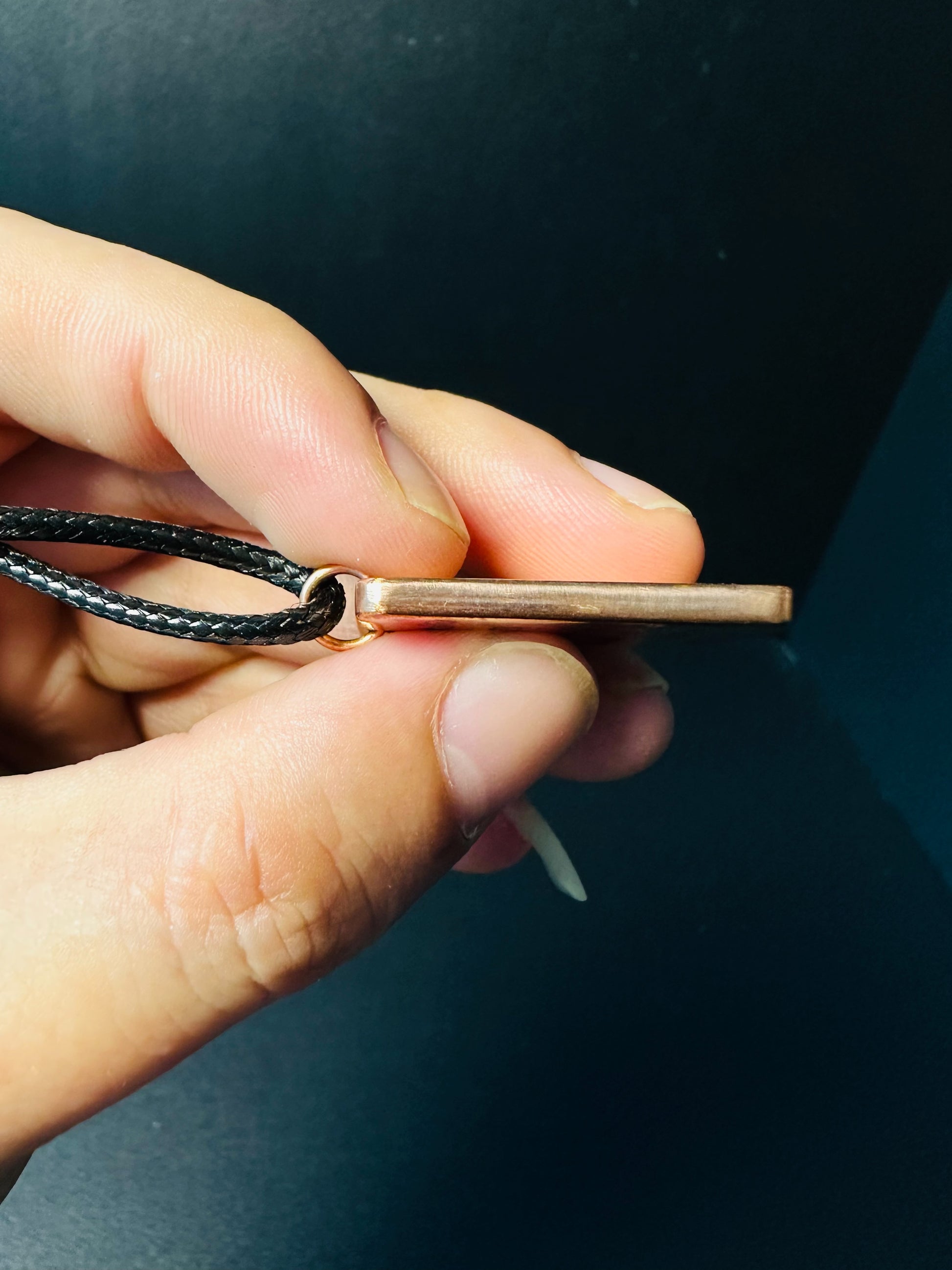 Side profile of the flat copper pendant showing its slim plate and cord loop