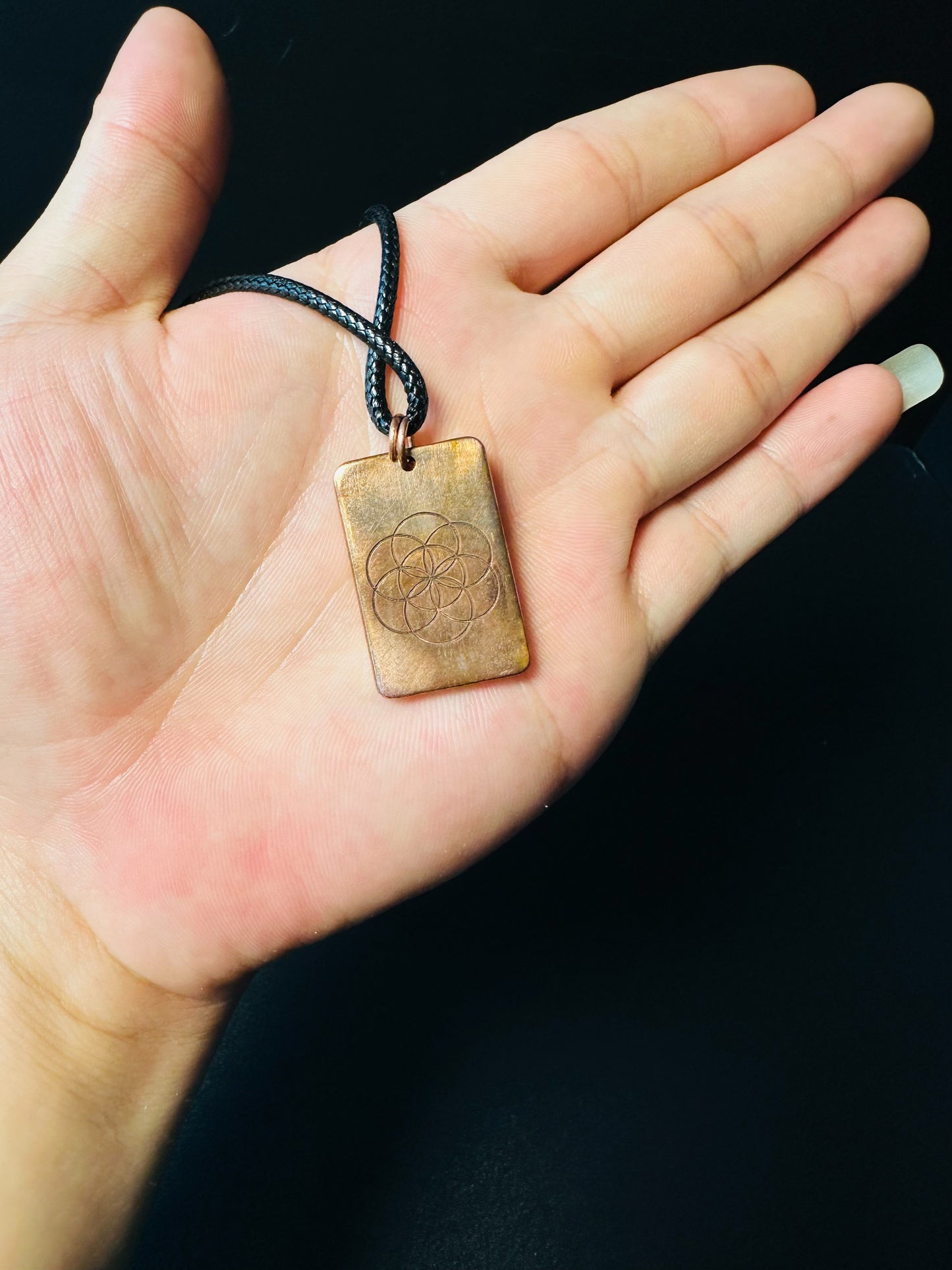 Copper Seed of Life pendant resting on a hand, showing everyday-wear scale