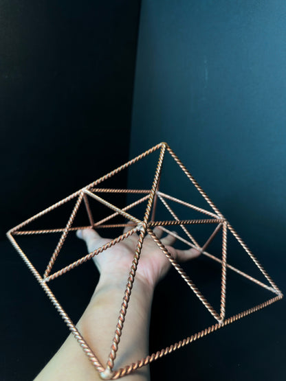 Large twisted copper wire pyramid held in hand, handmade crystal charging tool