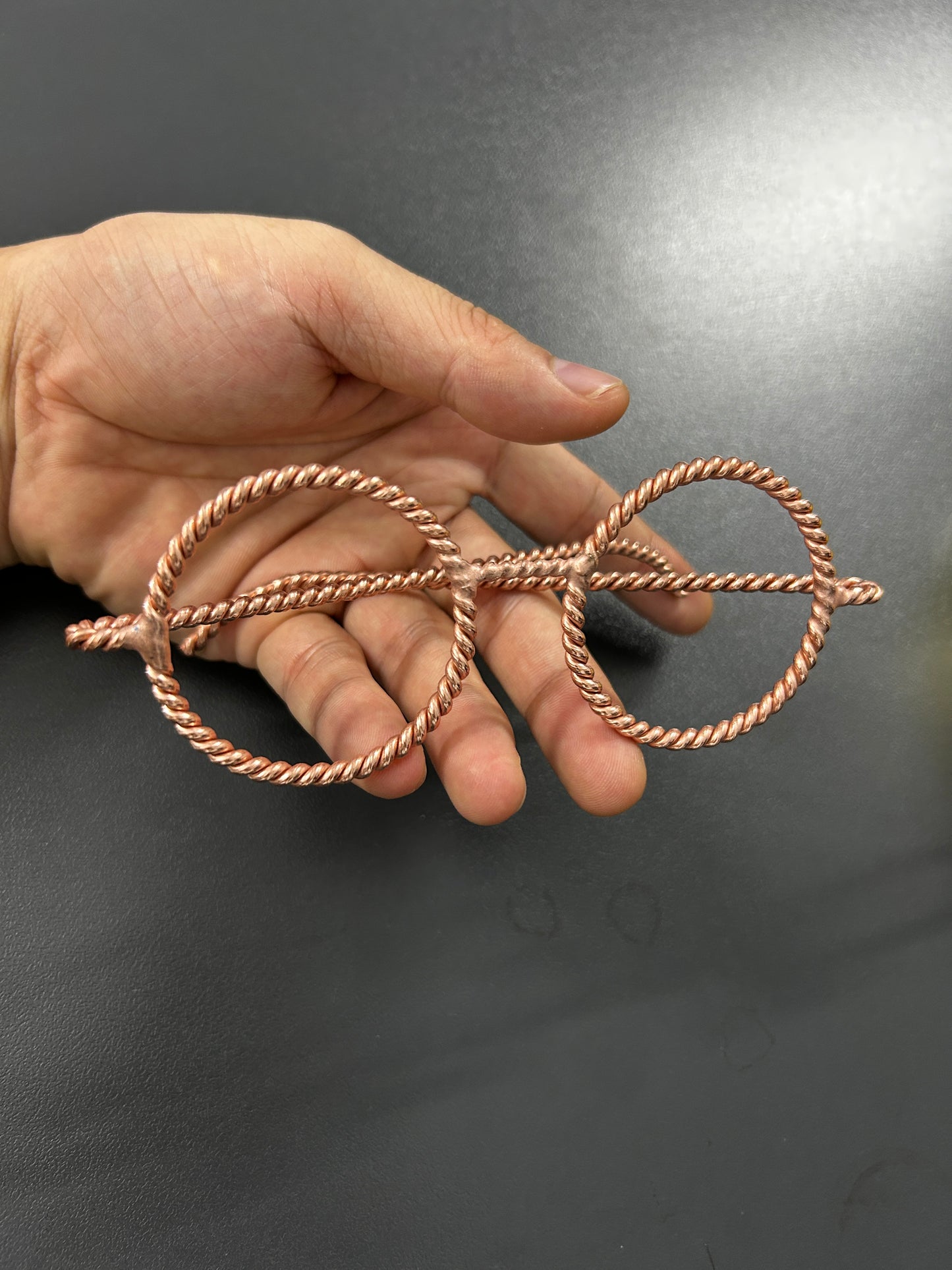 Handmade twisted copper tensor ring glasses held in hand showing size