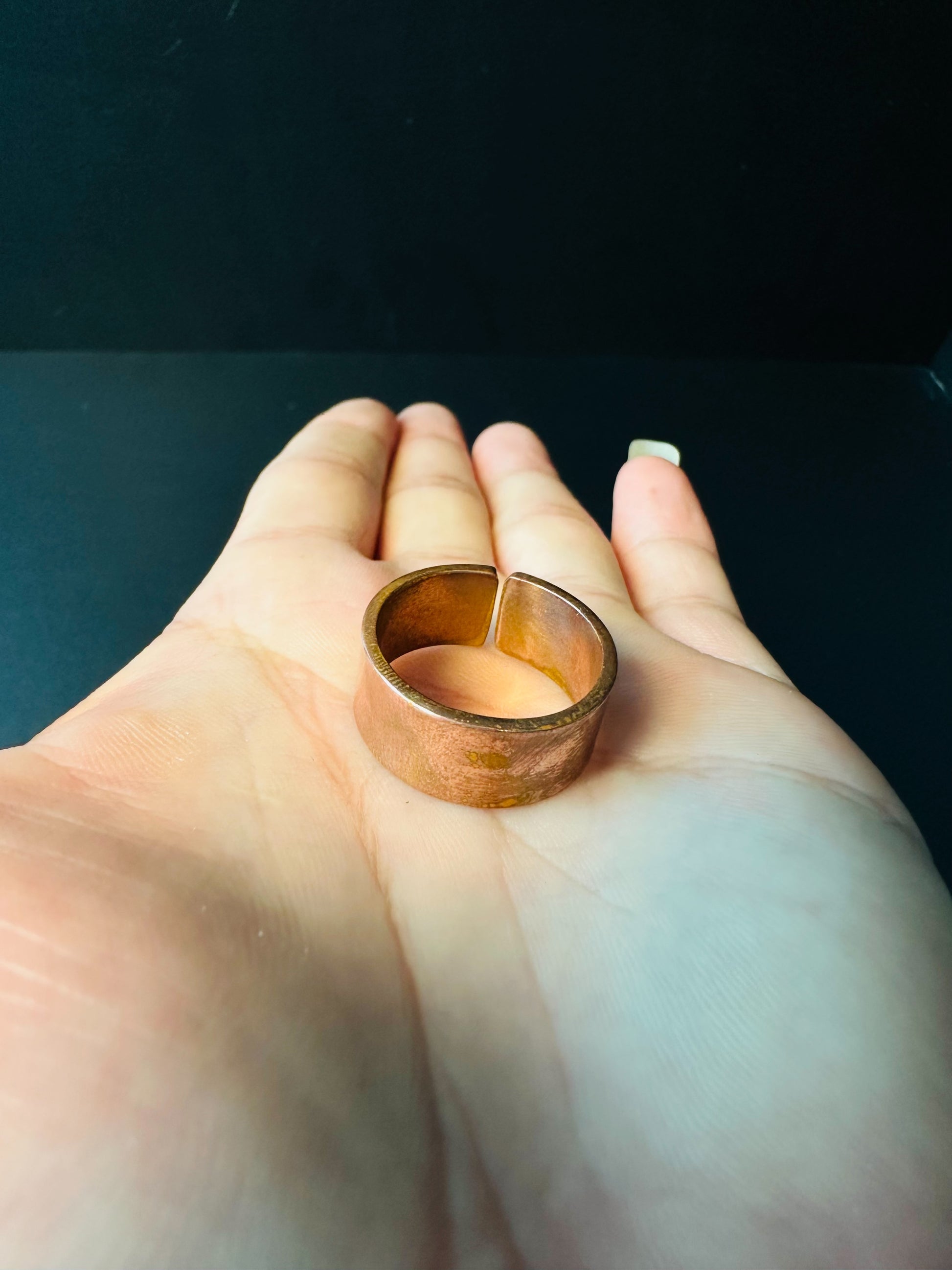 Wide copper ring resting on a palm, showing its band width and open back